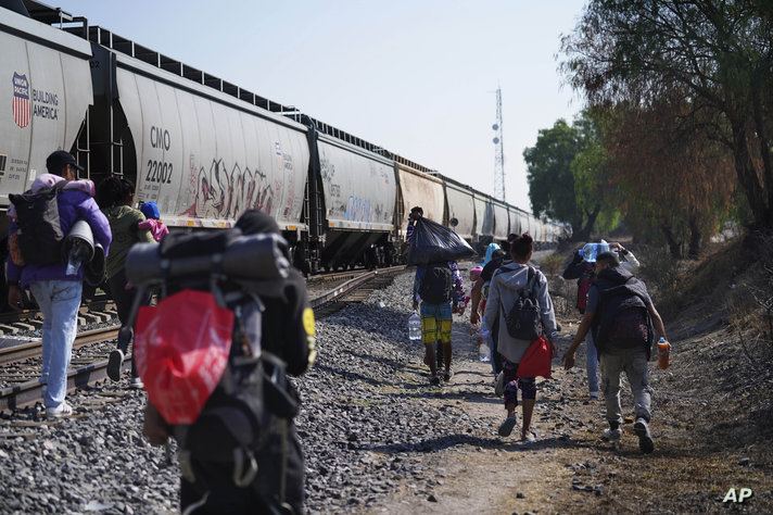 مهاجرون يسيرون على طول قطار يمر في هويهويتوكا المكسيك